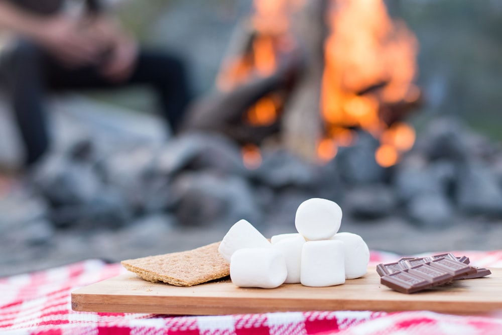 Marshmallows e barra de chocolate em tábua de madeira marrom