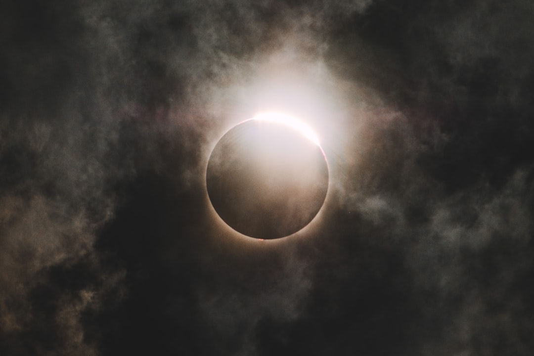 A solar eclipse darkening the sky as clouds passed by it.