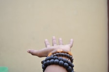 person hand with black beaded bracelets