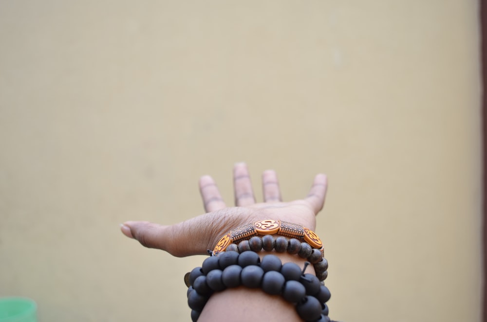 person hand with black beaded bracelets