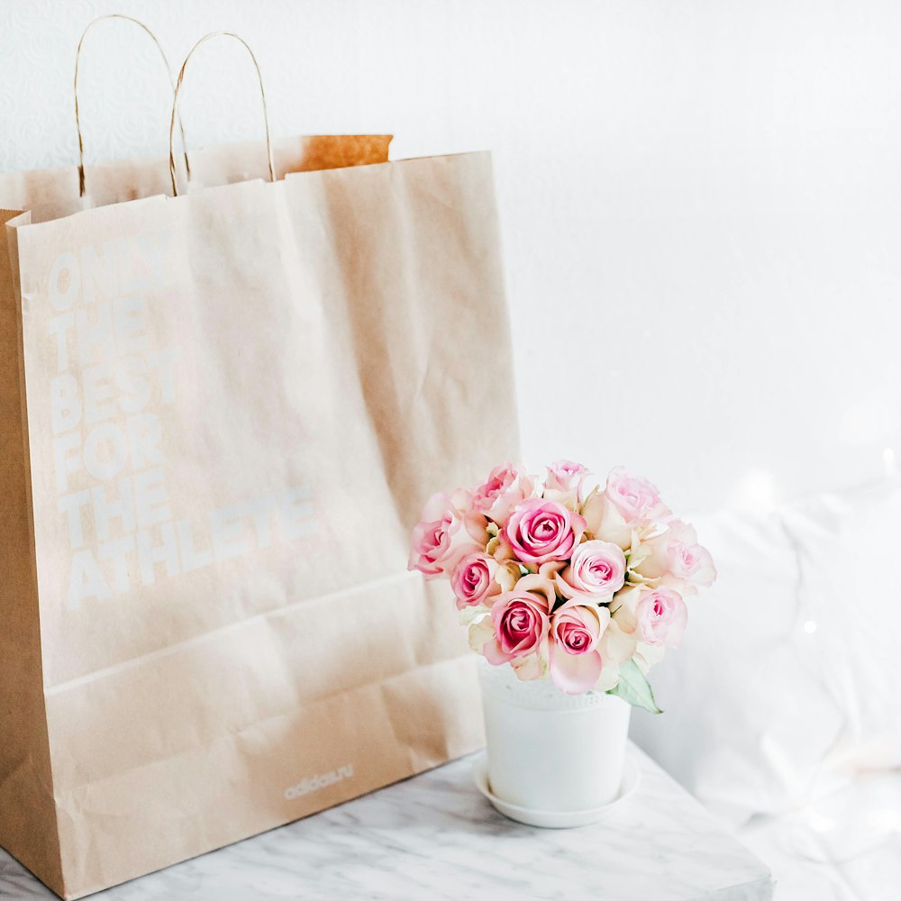 ramo de rosas rosas junto a bolsa de papel marrón