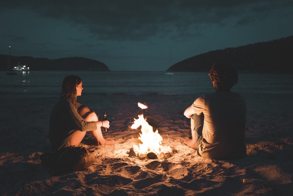 바닷가에 앉아 있는 뼈 불을 가진 남자와 여자