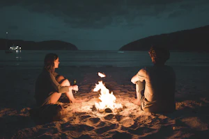 couple laughing by a beach bonfire