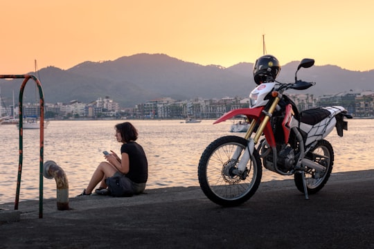 girl sitting at the edge of the dock near motocross bike during day in Marmaris Turkey