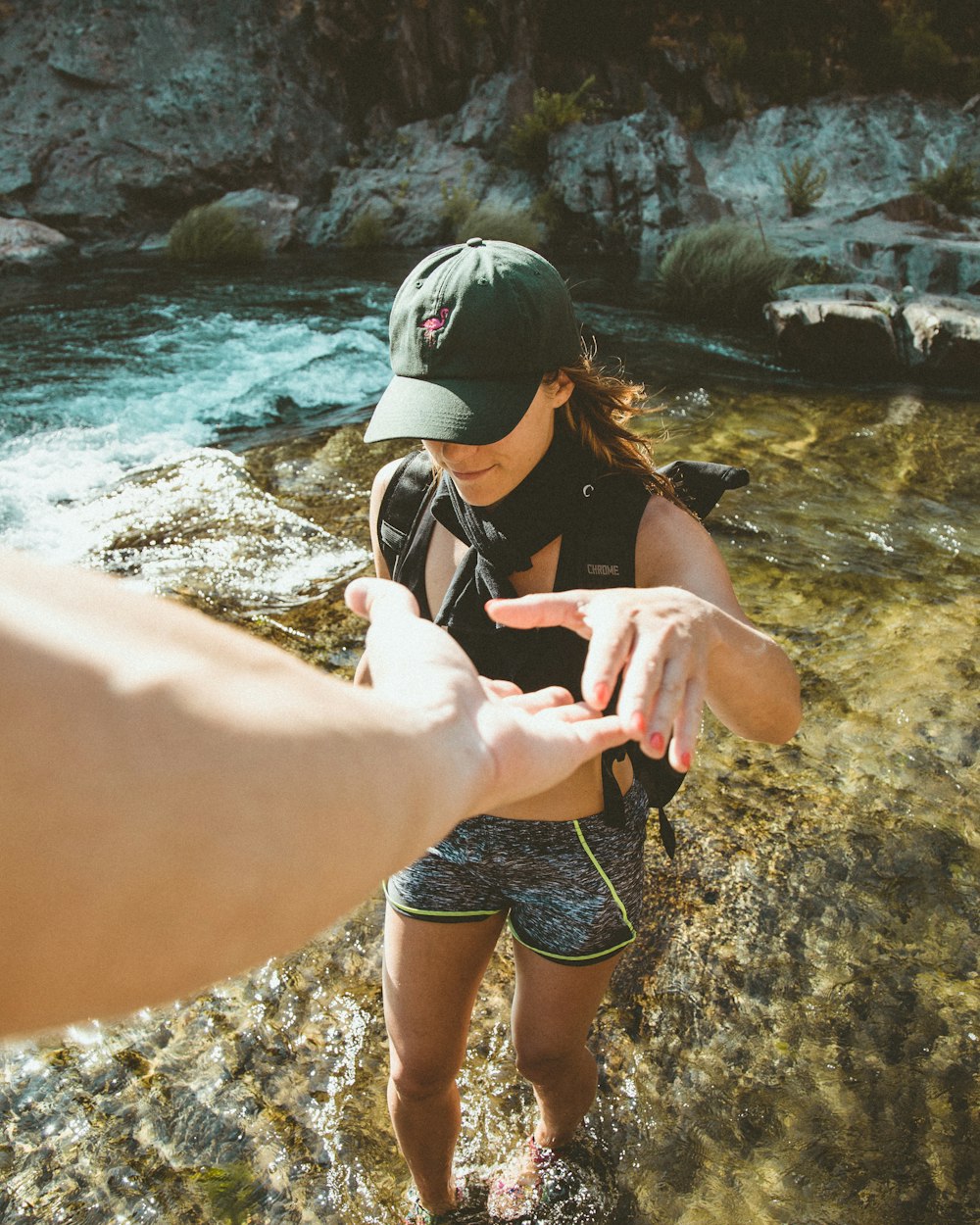 woman standing on body of water about to hold person's hand