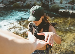 woman standing on body of water about to hold person's hand