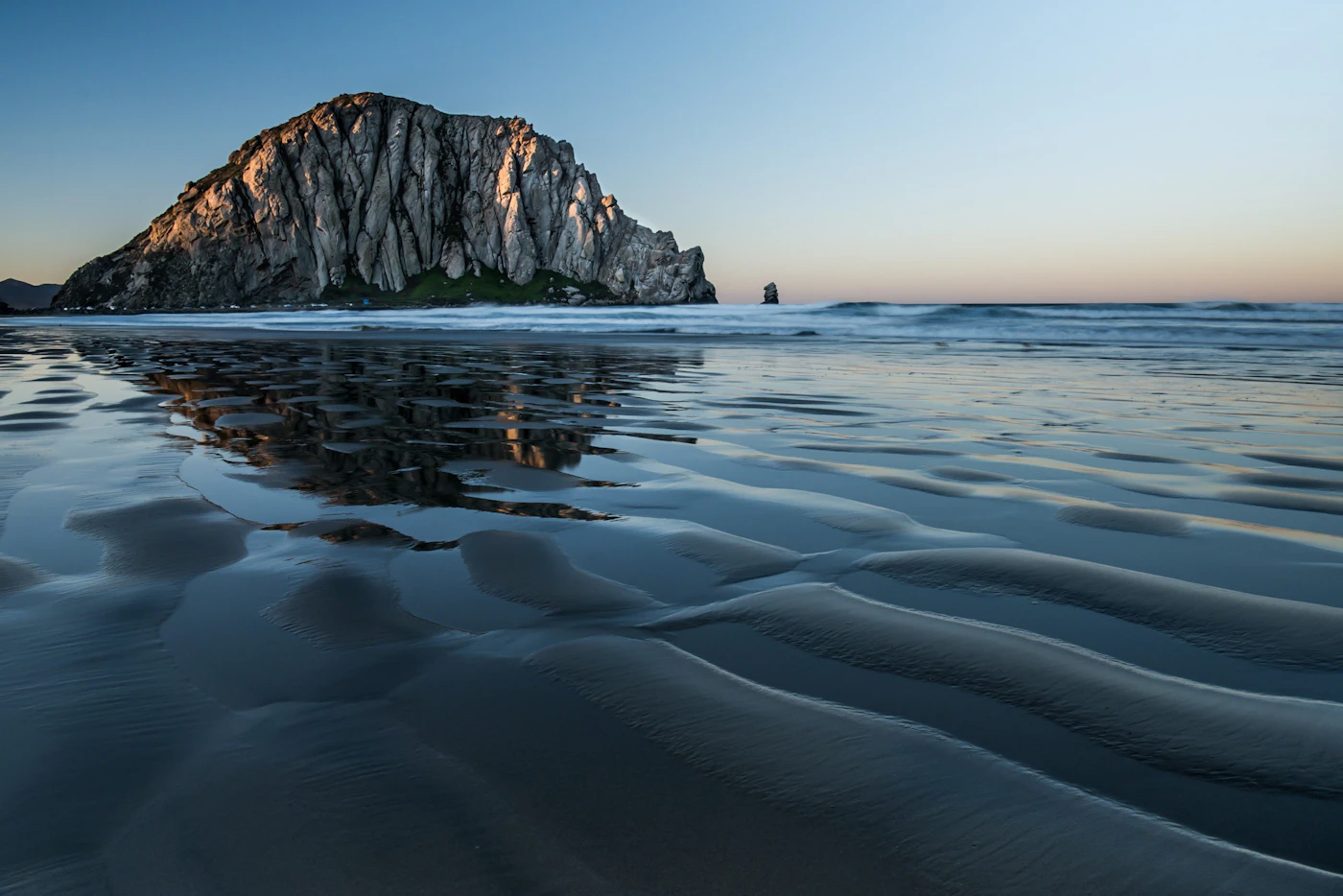 Morro Rock rising above the water at Morro Bay in soft evening light.