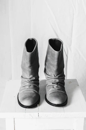 Side-by-side comparison of worn-out and restored leather boots on a wooden surface.
