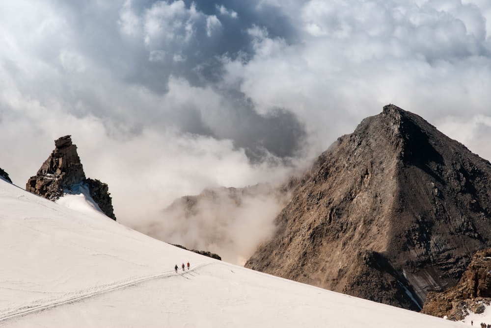 雲の浮かぶアルプス山を歩く人々