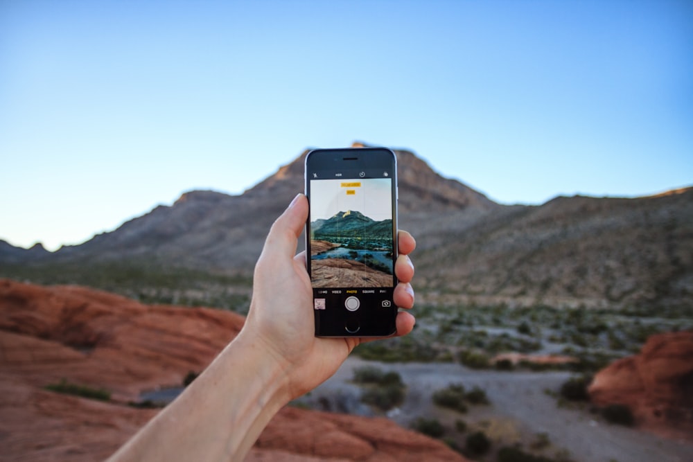 person taking a picture of mountain