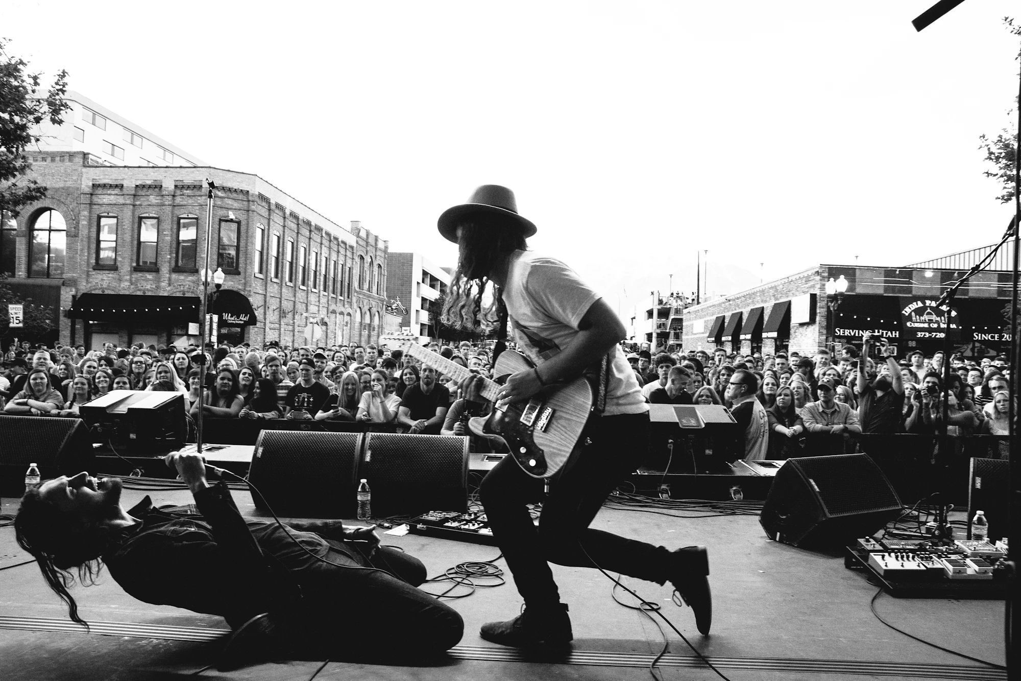 Black and white photo of the band on an outdoor stage in front of a big afternoon crowd