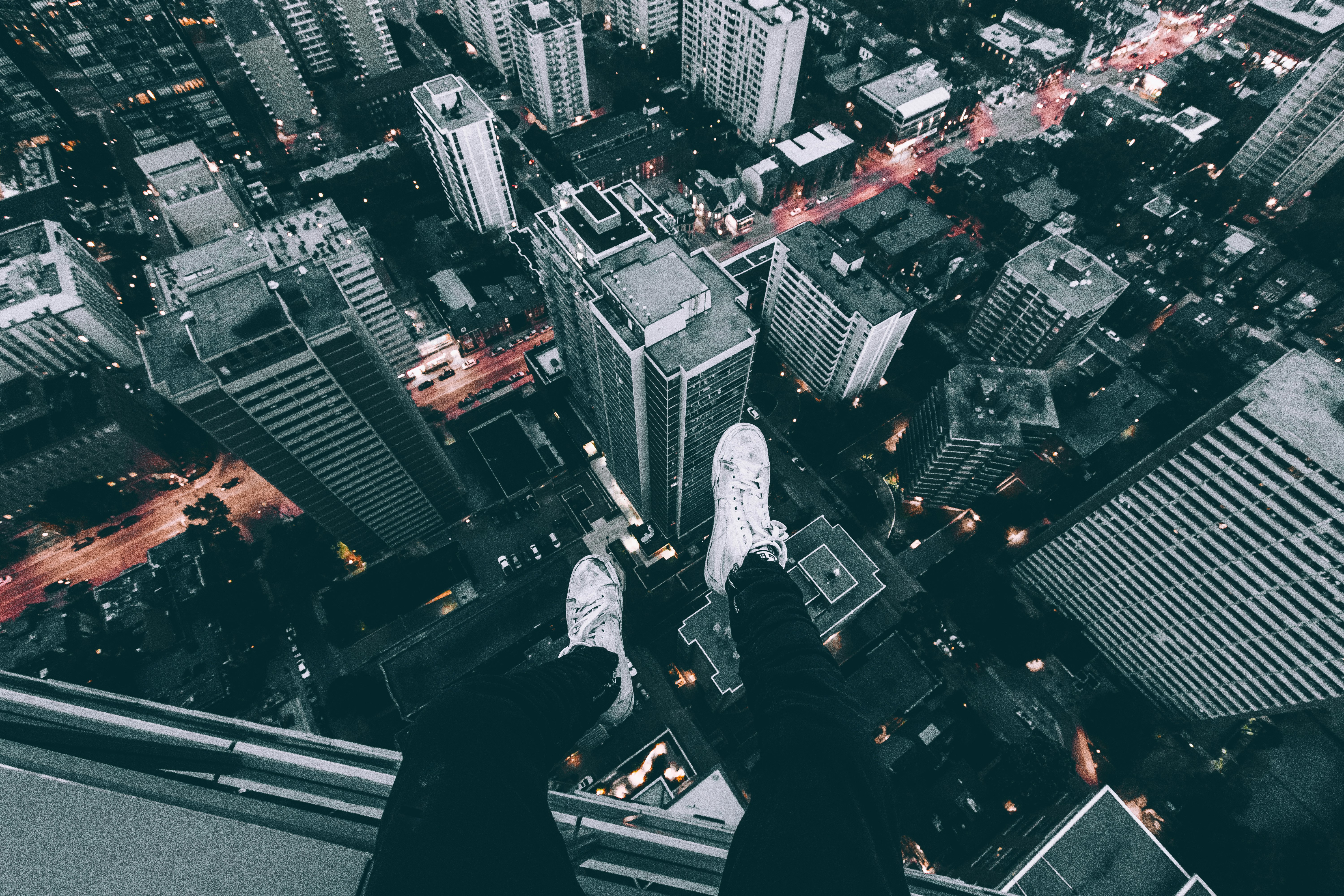 aerial photography of man sitting on top of building with high rise buildings view at daytime