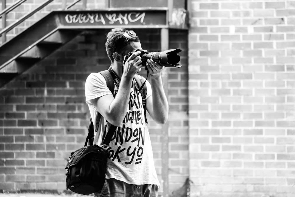 man capturing photograph with DSLR camera standing near stairway
