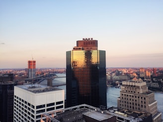 A striking skyline view featuring a newly completed skyscraper with glass facades reflecting the sunset.