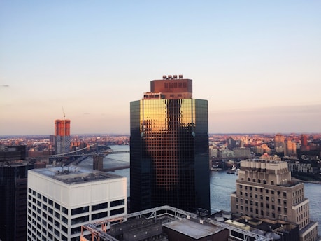 A striking skyline view featuring a newly completed skyscraper with glass facades reflecting the sunset.