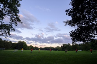 A joyful moment as kids play soccer in an open field under a clear sky.