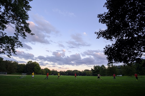 A joyful moment as kids play soccer in an open field under a clear sky.