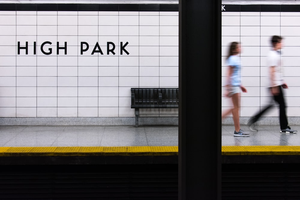 man and woman walking away from High Park signage