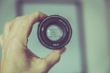 a hand holding a camera lens in front of a picture frame