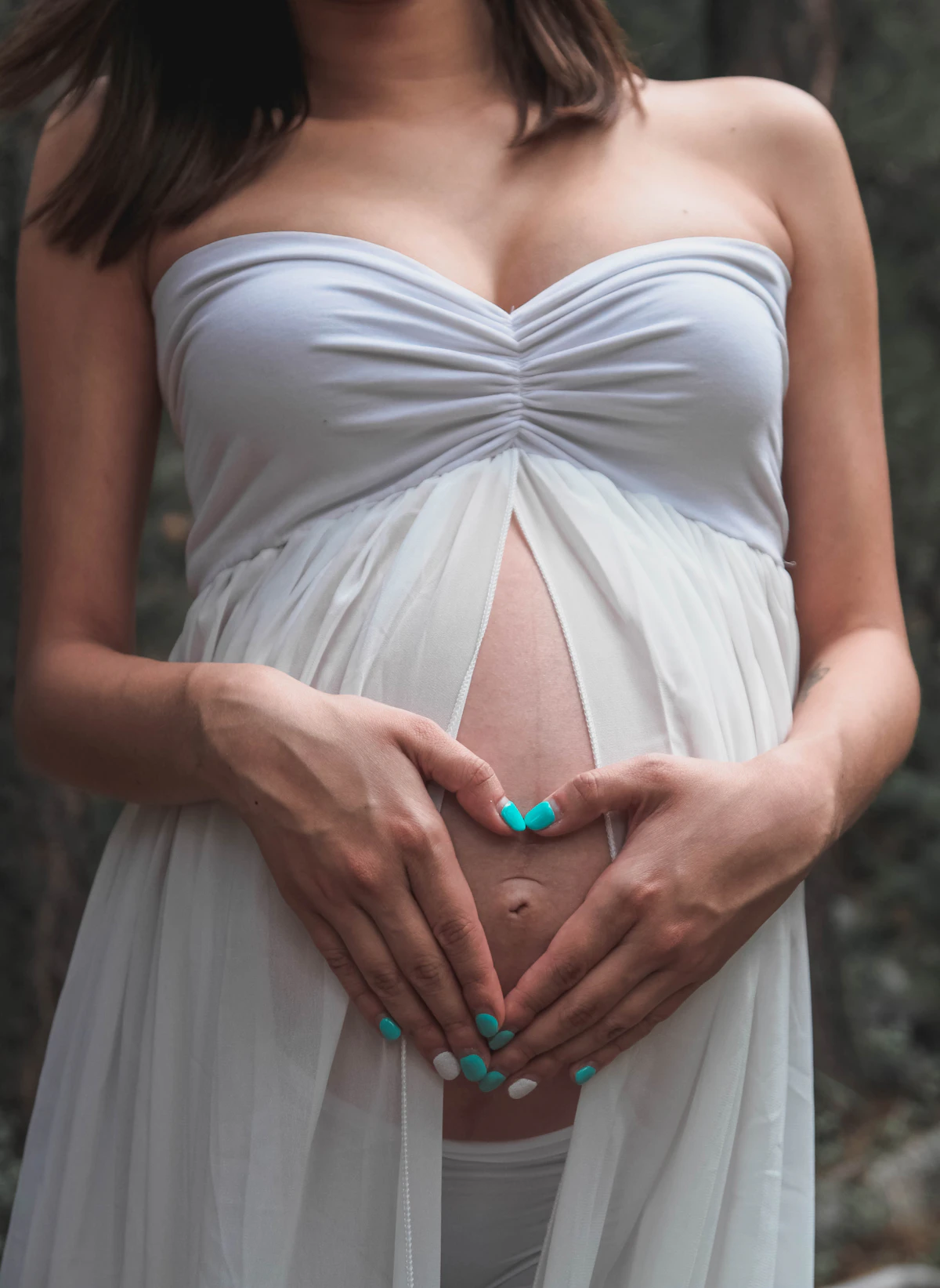 Pregnant woman gently holding her belly with both hands