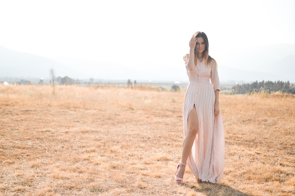 woman wearing dress standing on field under white sky