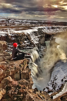 person sitting on top of multi-step waterfalls