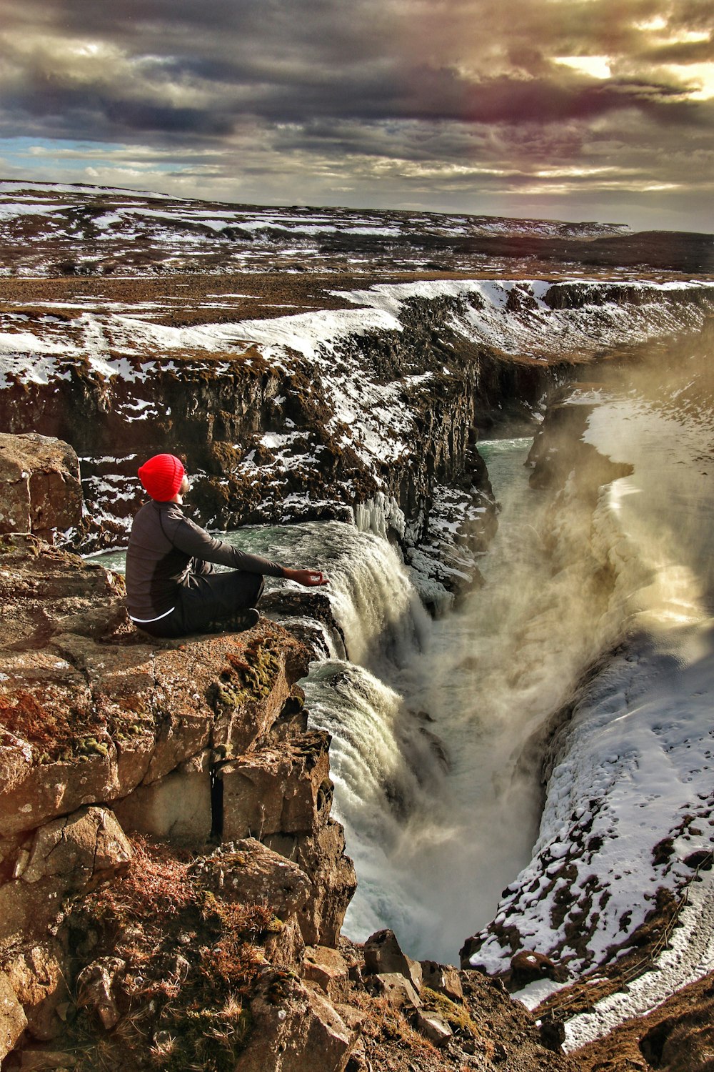 person sitting on top of multi-step waterfalls