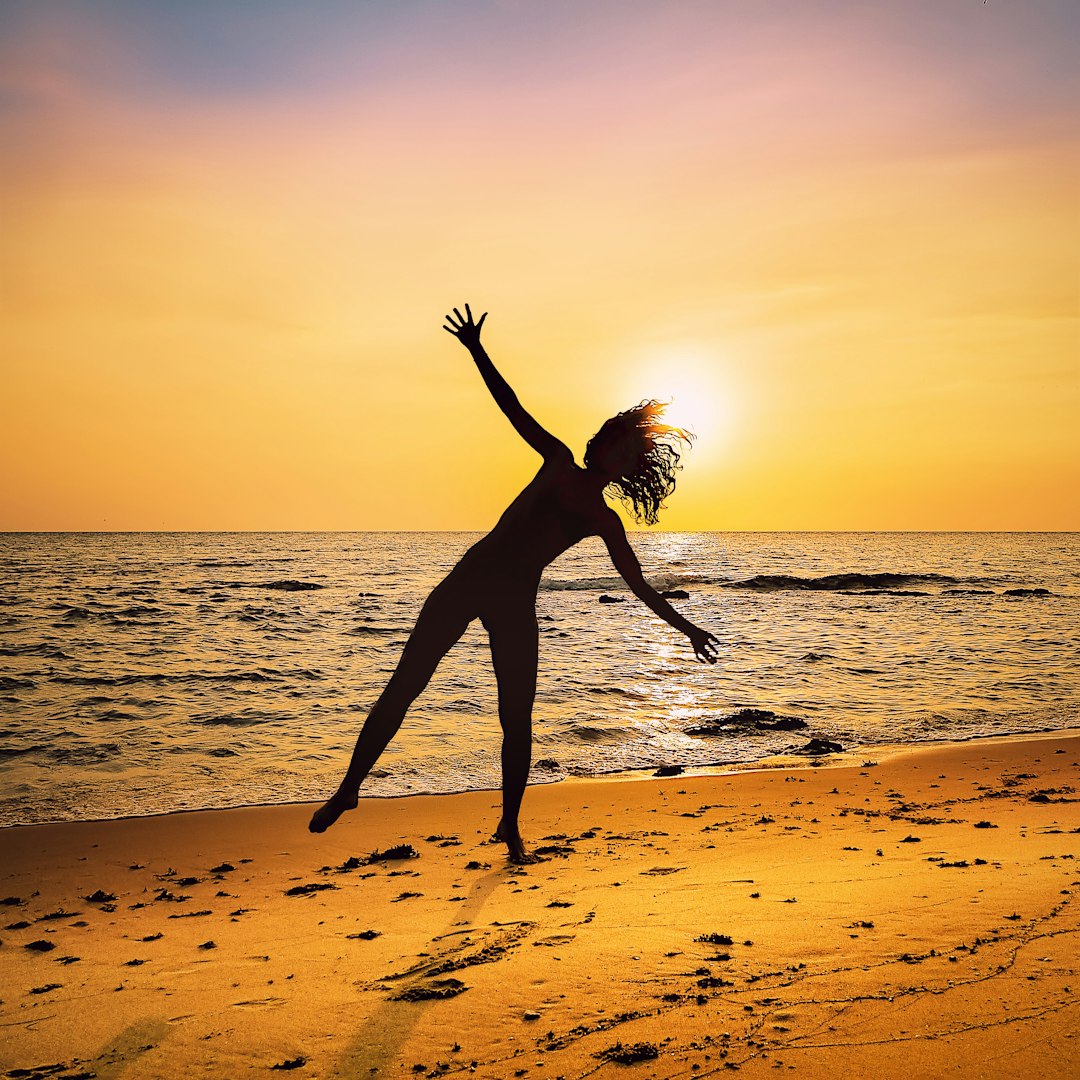 A woman about to do a cartwheel on the beach.