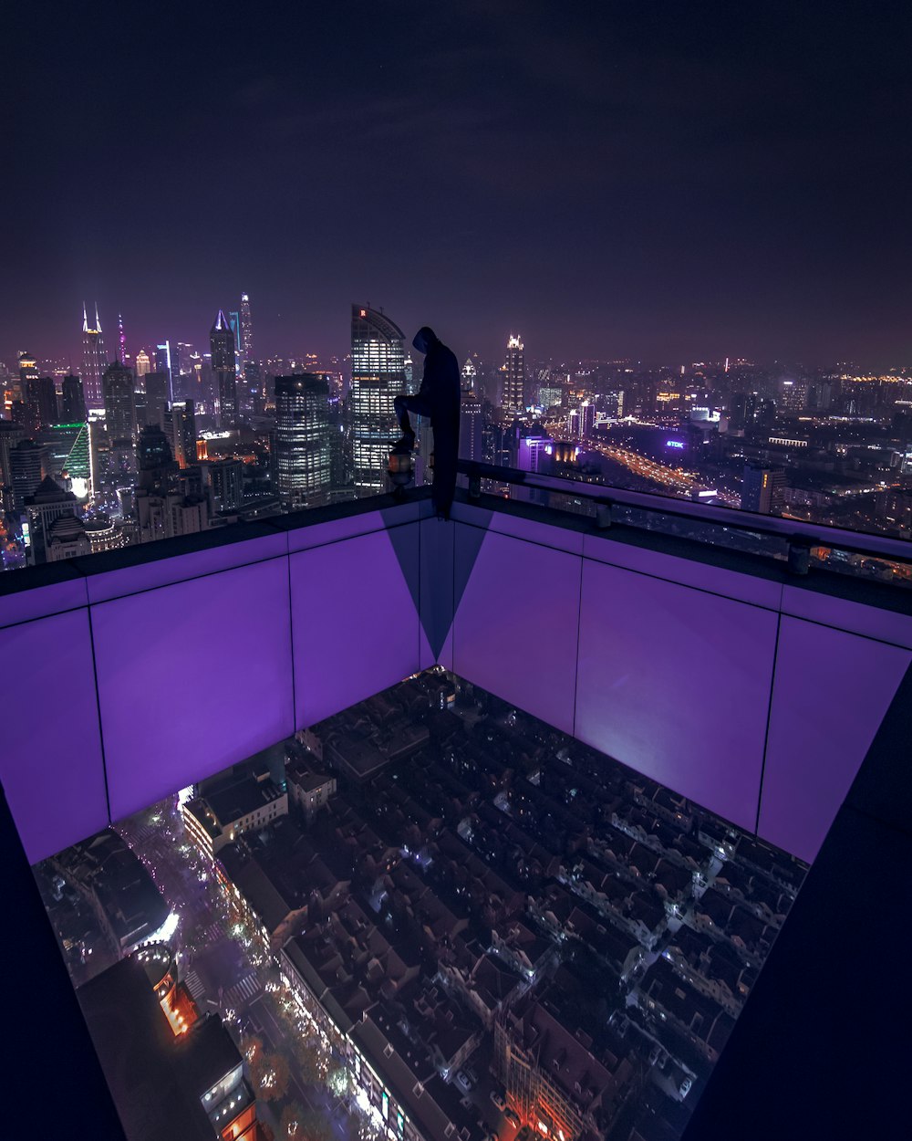 uomo in piedi sul tetto dell'edificio durante il tempo di notte
