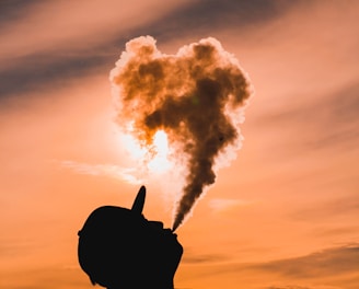 silhouette of man vaping during sunset