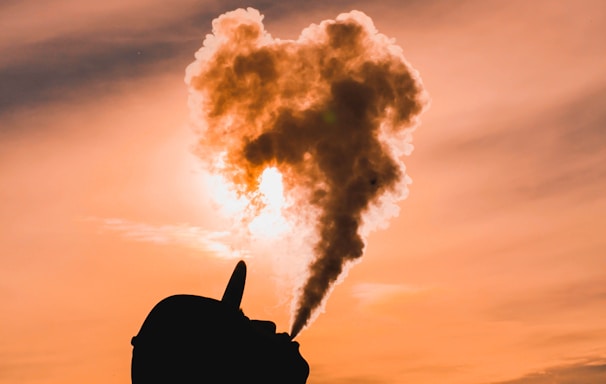 silhouette of man vaping during sunset