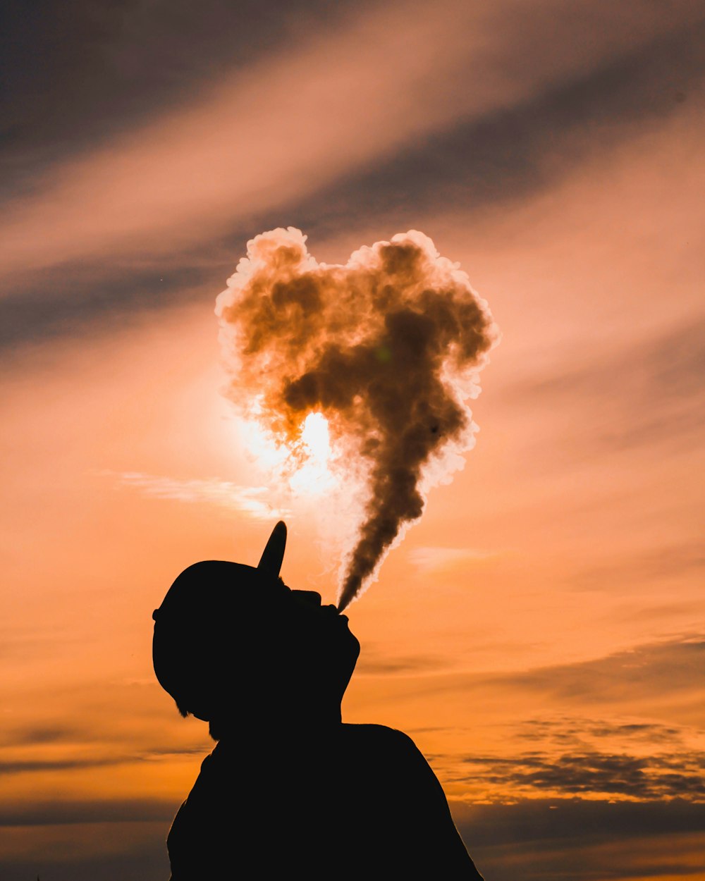 silhouette of man vaping during sunset