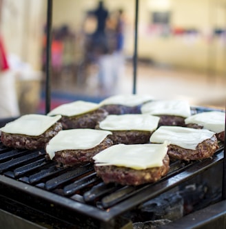 selective focus photography of meat patty with cheese on grill