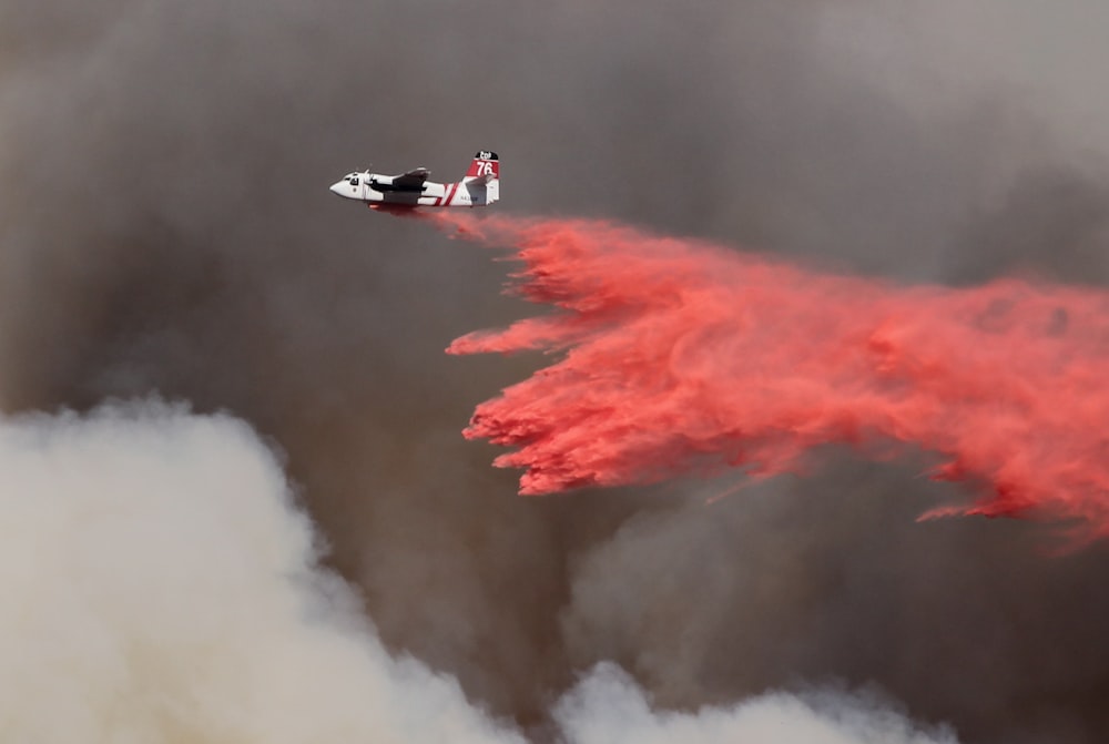 aeroplano bianco e rosso che versa polvere rossa sul fuoco