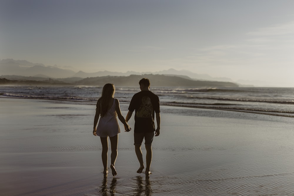 homme et femme se tenant la main en marchant sur un plan d’eau