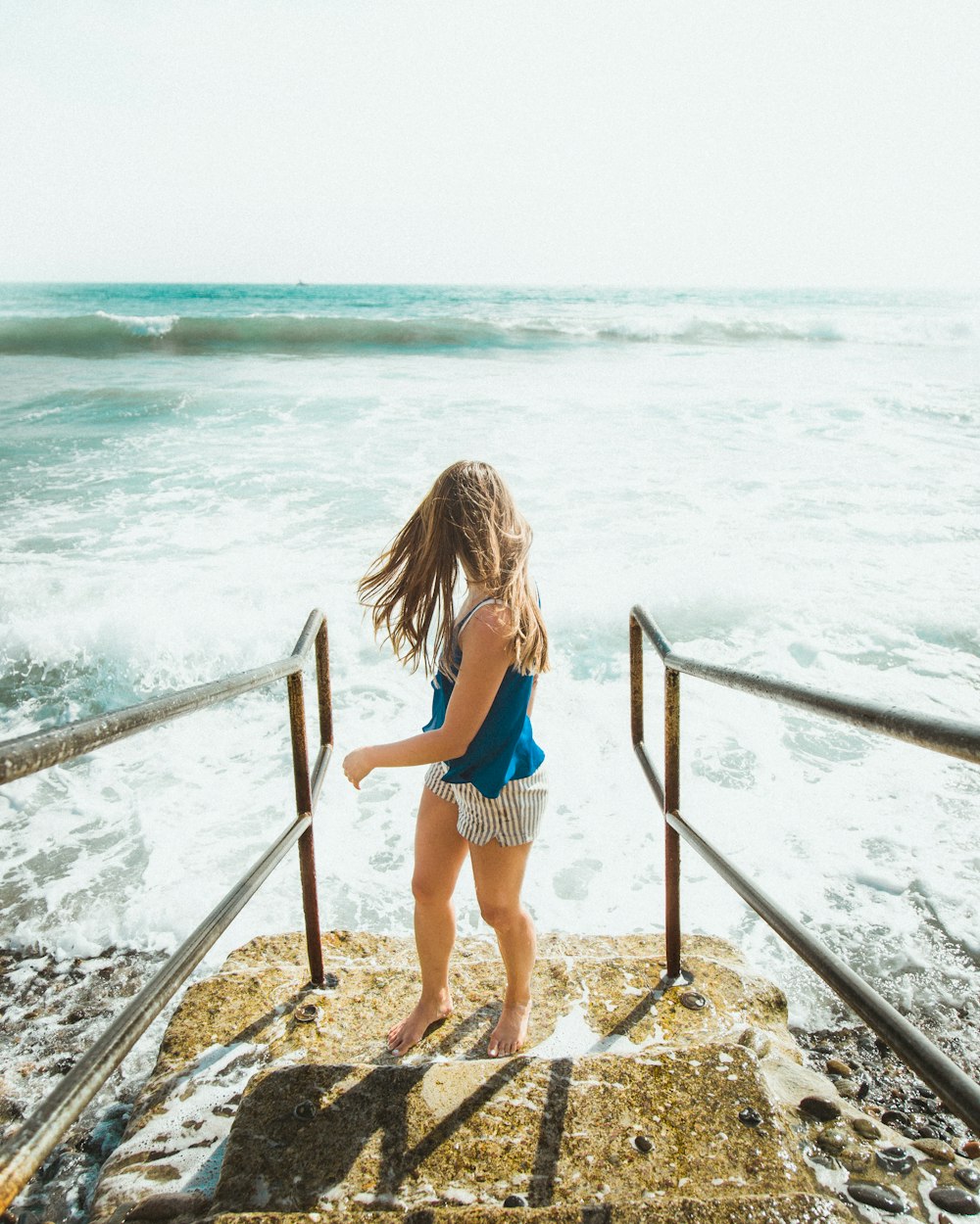 a little girl standing on a beach next to the ocean