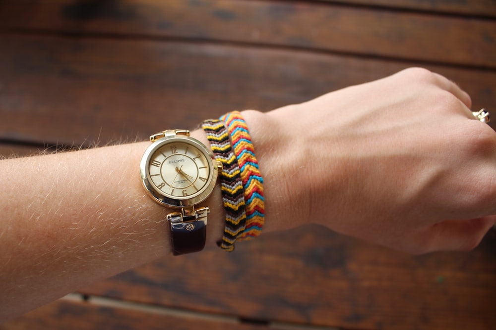 person wearing gold-colored analog watch with black strap