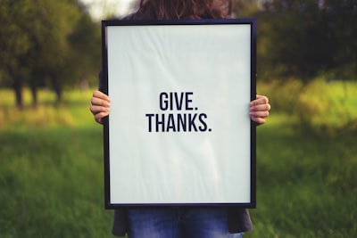 person holding rectangular black wooden photo frame with give. thanks. print thanksgiving day zoom background