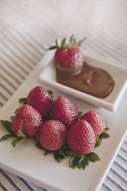 platter of strawberries with chocolate dip on on white surface
