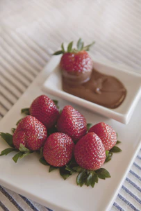 Close-up of fresh strawberries dipped in rich, glossy chocolate arranged on a rustic wooden board.