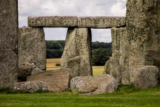 rock formation on green grass field with trees at the distance at daytime in Stonehenge United Kingdom