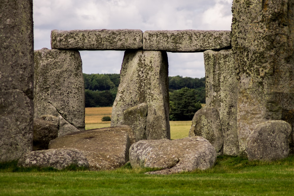 rock formation on green grass field with trees at the distance at daytime