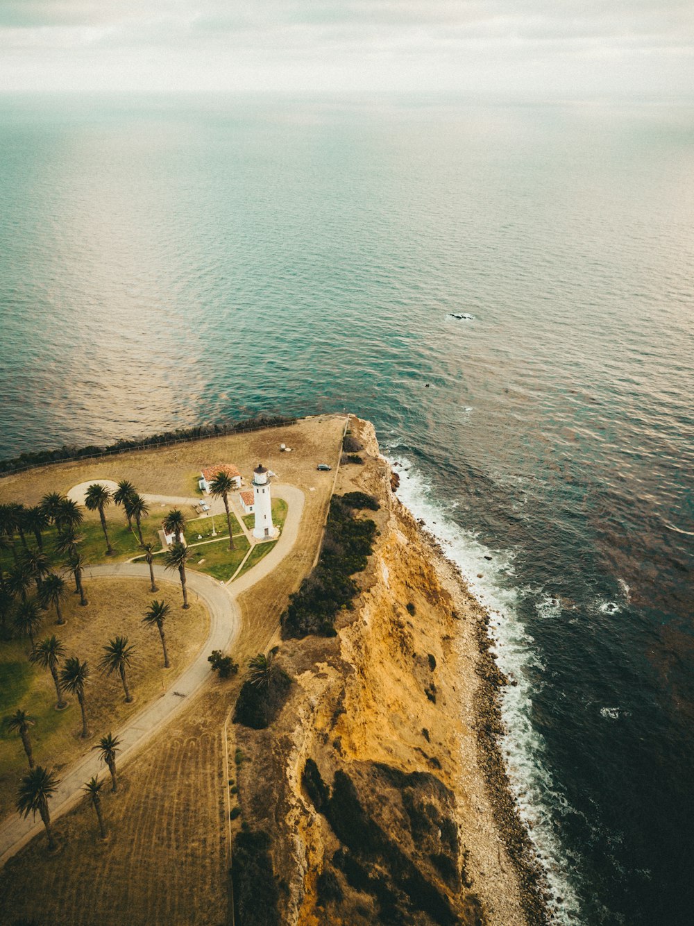 Phare blanc près du plan d’eau pendant la journée