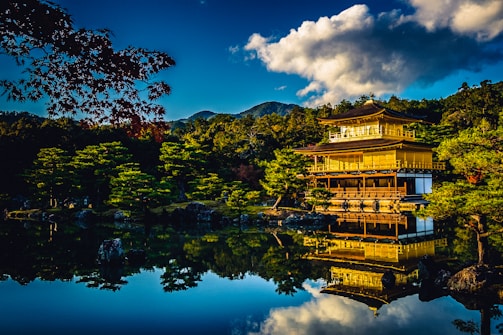 A peaceful temple surrounded by lush greenery and golden statues shining in the sunlight.