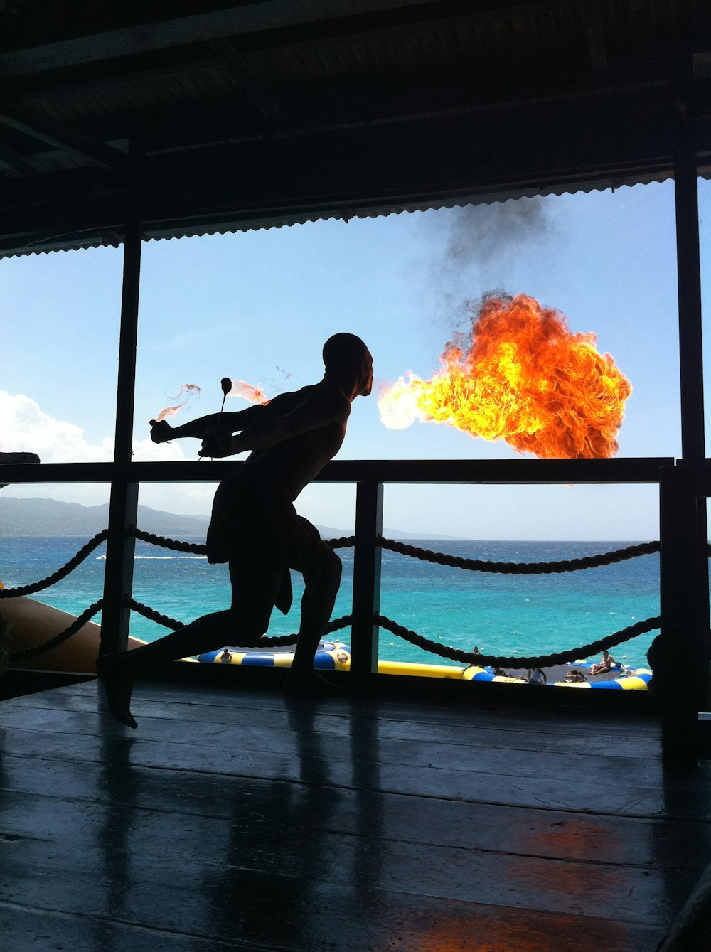 a person standing on a deck with a fire in the background