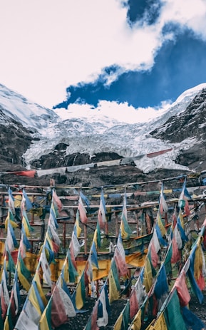 multicolored streamers near snow mountain under blue and white cloudy sky