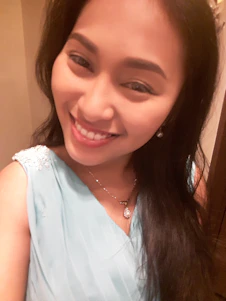 A warm, inviting photo of a woman wearing a stylish blouse from Luzara, smiling confidently in natural light.