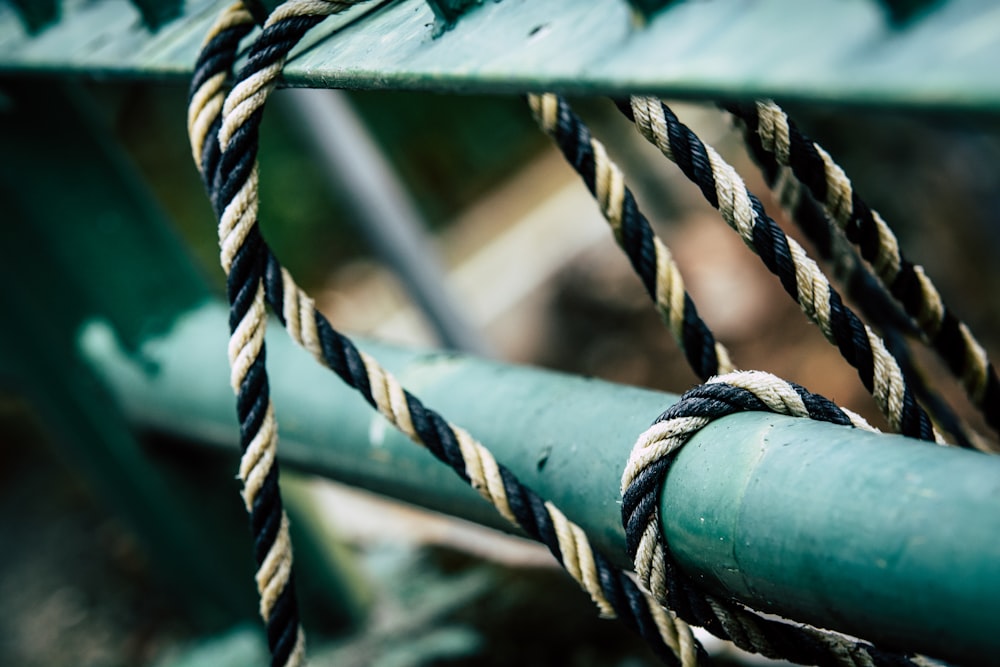 closeup photo of tie black rope on green metal rod
