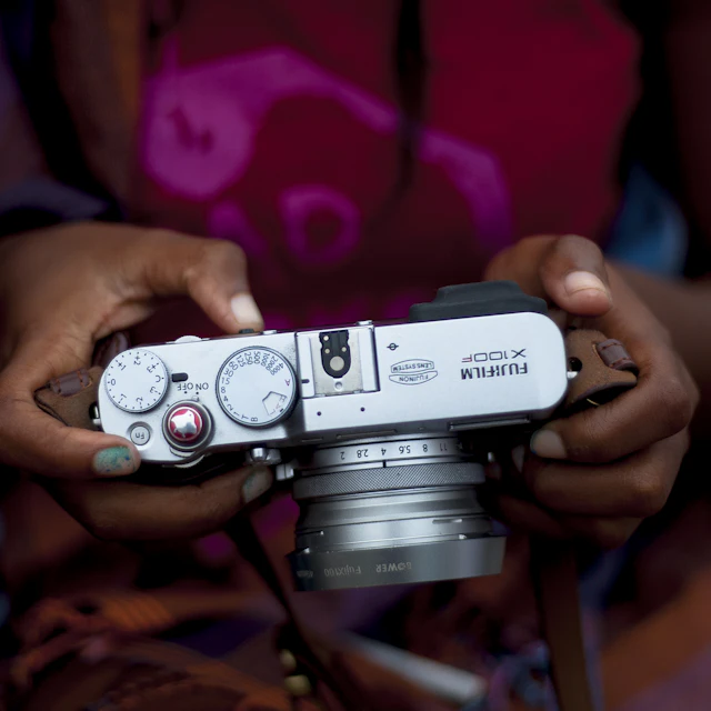 Woman holding a gray Fujifilm X100 series compact camera