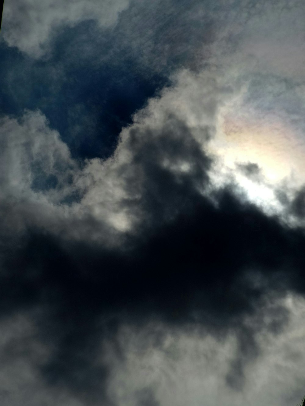 a plane flying through a cloudy sky with a rainbow in the sky